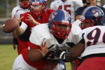 Liberty quarterback Tyler Newman, in red, reaches for the snap during practice.