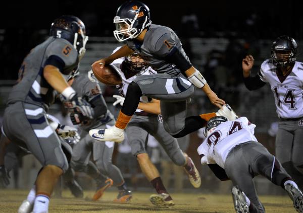 Legacy’s quarterback Devin Williams (1) jumps over Cimarron-Memorial’s Javon Mar ...