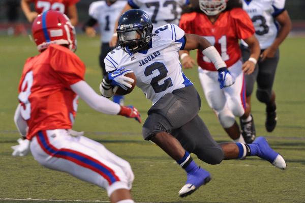 Desert Pines running back Eric Wilkes (2) cuts between Valley defenders Iyen Medlock (9) and ...