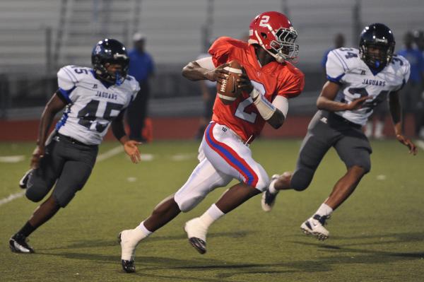 Valley quarterback Tyrone Prewitt (2) scrambles away from Desert Pines defenders Tevin Moore ...