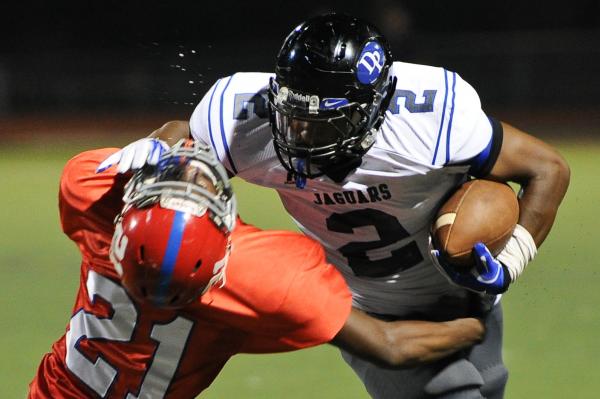 Desert Pines running back Eric Wilkes (2) stiff arms Valley defender Malik Batiste (21) on T ...