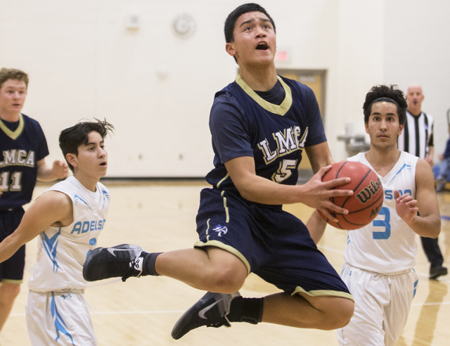 Lake Mead’s Kai Madela (5) makes an acrobatic layup over Adelson School’s Jacob ...