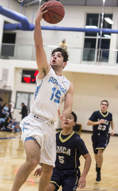 Adelson School’s Jake Buchman (15) converts a fast break layup past Lake Mead’s ...