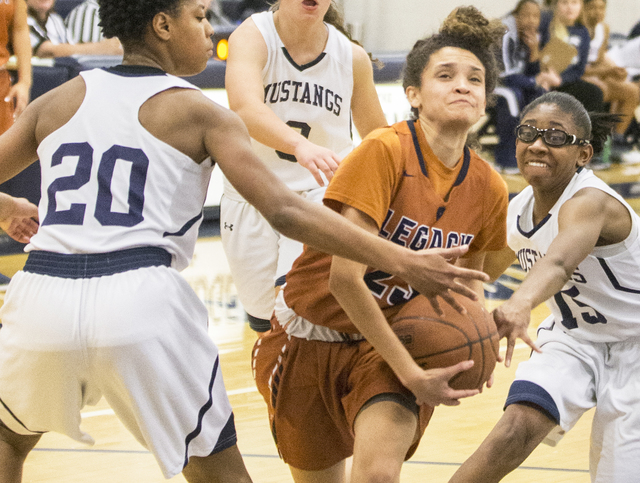 Legacy’s Rory Carter (23) splits Shadow Ridge defenders Summer Plunkett (20) and Amai ...