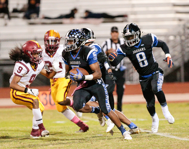 Desert Pines senior Eddie Heckard (5) runs the ball while avoiding Del Sol defenders during ...