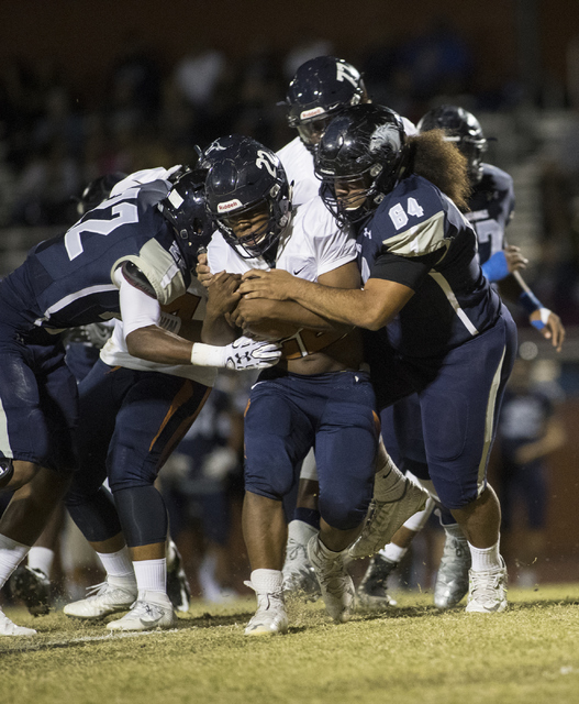 Samuel Turner (22) runs the ball through Shadow Ridge defenders Aubrey Nellems (22) and Jayd ...