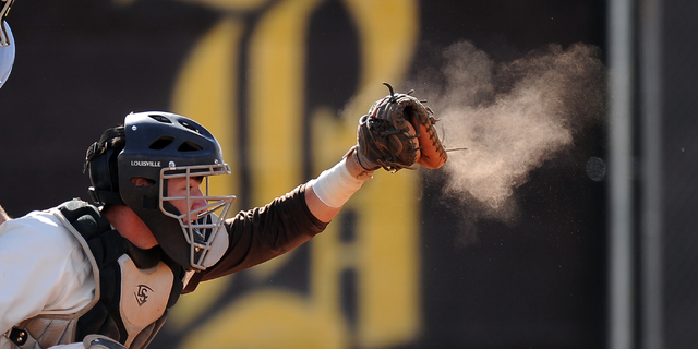 Dust flies off of the catcher’s mitt worn by Bonanza’s Hunter Junge after catchi ...