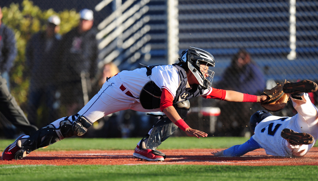 Centennial base runner Garrett Holden slips under the tag of Liberty catcher Daniel Gonzales ...