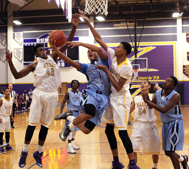 Canyon Springs guard Jordan Davis (1) goes up for a shot between Durango forwards Zyare Ruff ...