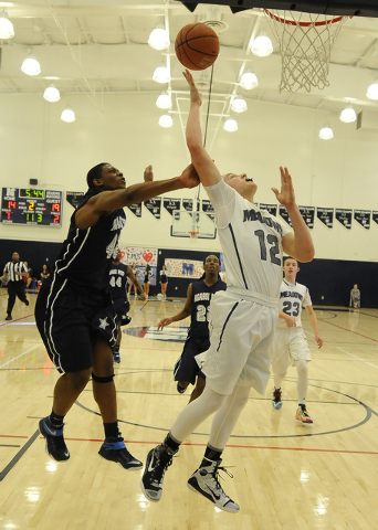 Agassi Prep forward Darius Coaxum, left, fouls The Meadows School guard Ethan Fridman (12) i ...