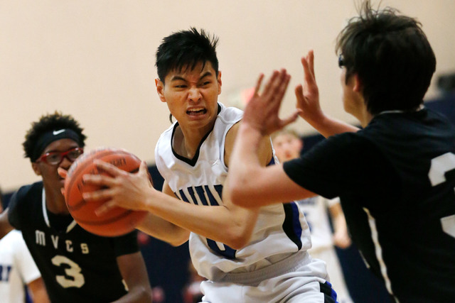 Calvary Chapel’s Marior Munda, center, keeps a ball away from Mountain View’s Da ...