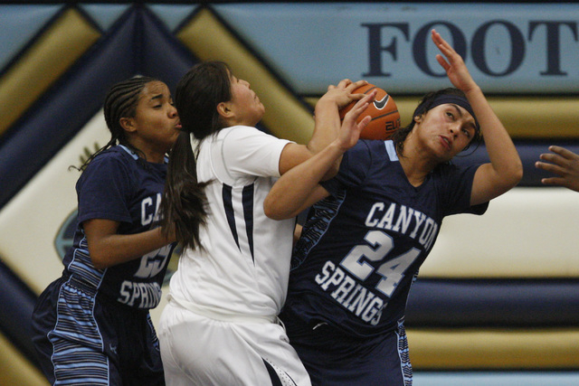 Canyon Springs’ D’Licya Feaster, left, and Daijhan Cooks fight for a rebound wit ...