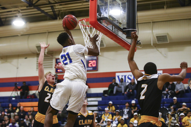 Bishop Gorman guard Christian Popoola (21) goes up for a shot between Clark guards Trey Wood ...