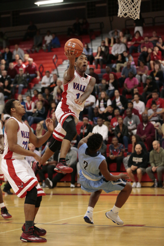 Valley senior Cameron Burton (10) drives up and over Canyon Springs senior Antonio Longmyers ...