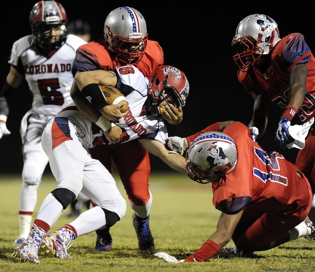 Liberty linebacker Bakari Speights, left, grabs the facemask of Coronado quarterback John Fa ...