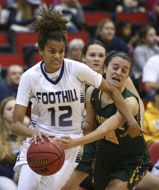 Foothill’s Rae Burrell (12) drives against Bishop Manogue forward Hannah Reviglio (14) ...