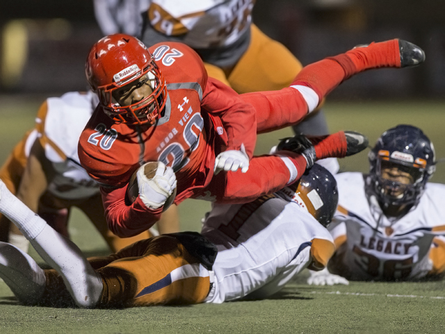 Arbor View’s Jaquari Hannie (20) leaps over Legacy defenders during the Sunset Region ...