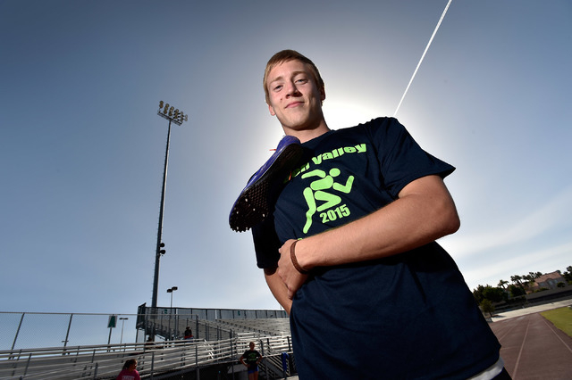 Ian Mack stands with his running spikes over his shoulder trackside at Green Valley High Sch ...