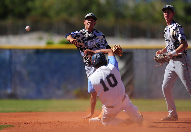 Shadow Ridge shortstop Eric Jordan turns a double play as Centennial base runner Frank Sessa ...