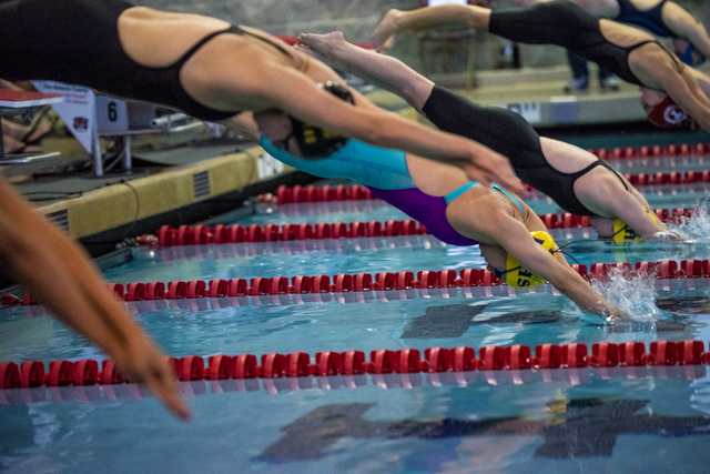 Montana Lloyd of Boulder City High School, center, dives into the water during the Nevada Hi ...