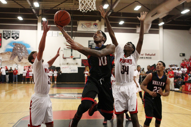 Valley guard Cameron Burton slips past Las Vegas guard Trevor Swenson, left, and Marquise Ra ...