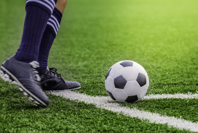 Kick off soccer ball with his feet on the football field