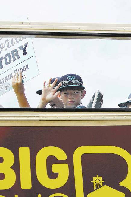 Mountain Ridge Little League players wave as they leave on a bus for their parade following a c ...