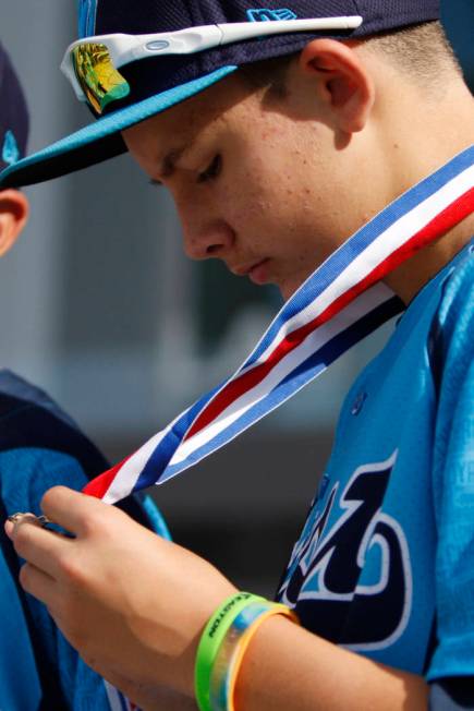 Mountain Ridge Little League player Andrew Matulich (14), right, looks at his medal as he stand ...