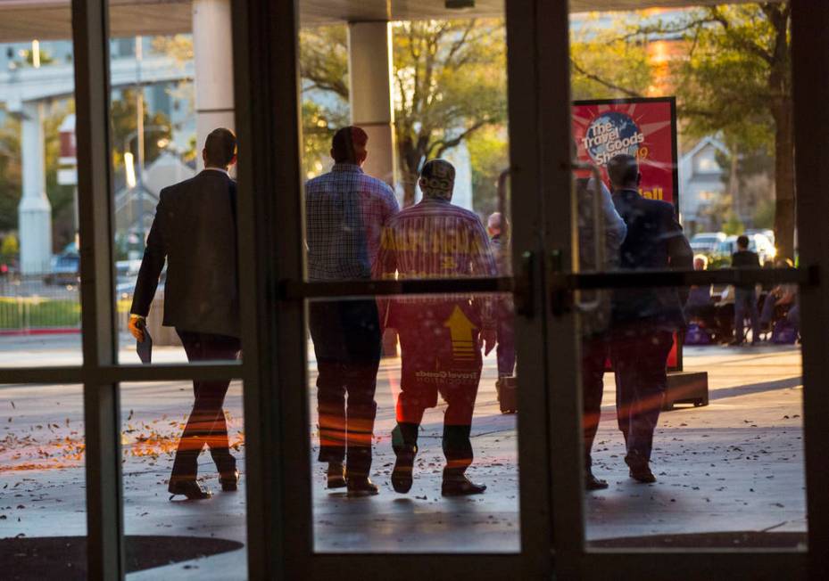 Plainclothes police officers walk out of the Las Vegas Convention Center after executing a sear ...