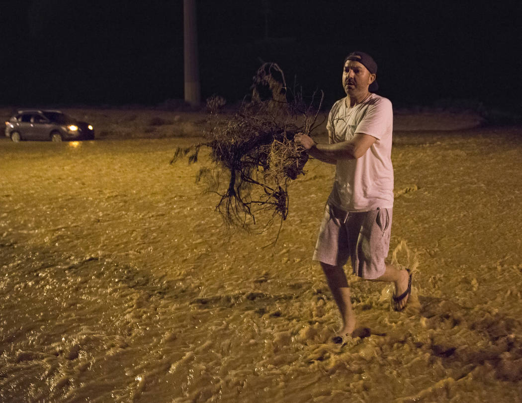 Jonathan Smedley runs through floodwaters with broken tree limbs to help his neighbors build a ...