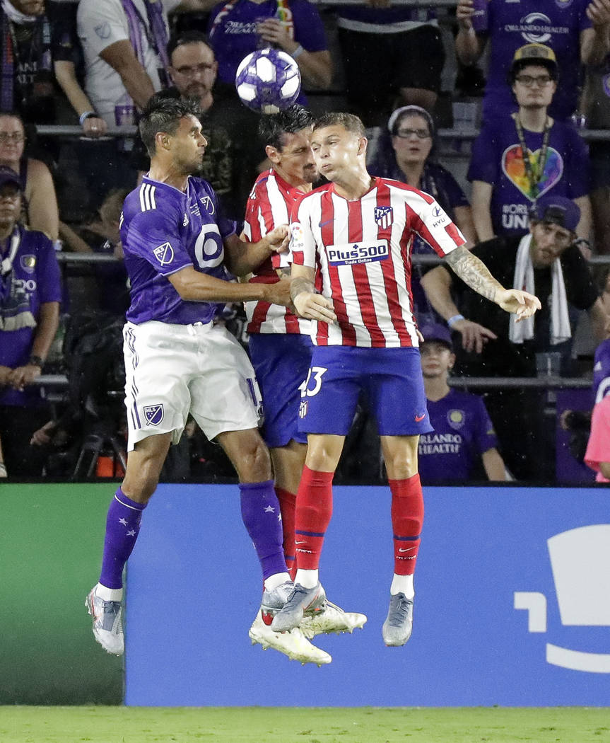 Atletico Madrid defenders Stefan Savic, center, and Kieran Trippier, right, go up for a header ...