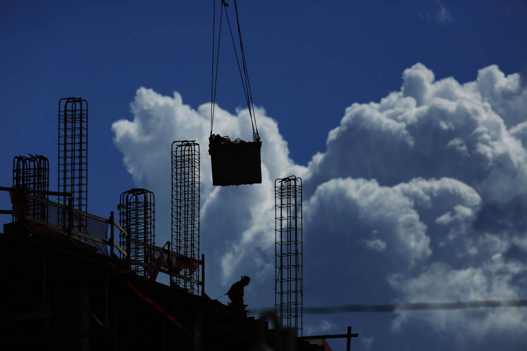 In this July 2, 2019, file photo a construction worker walks atop a building as a crane lifts a ...