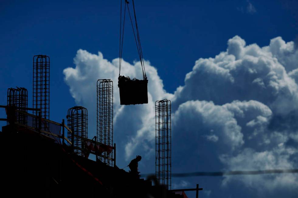 In this July 2, 2019, file photo a construction worker walks atop a building as a crane lifts a ...