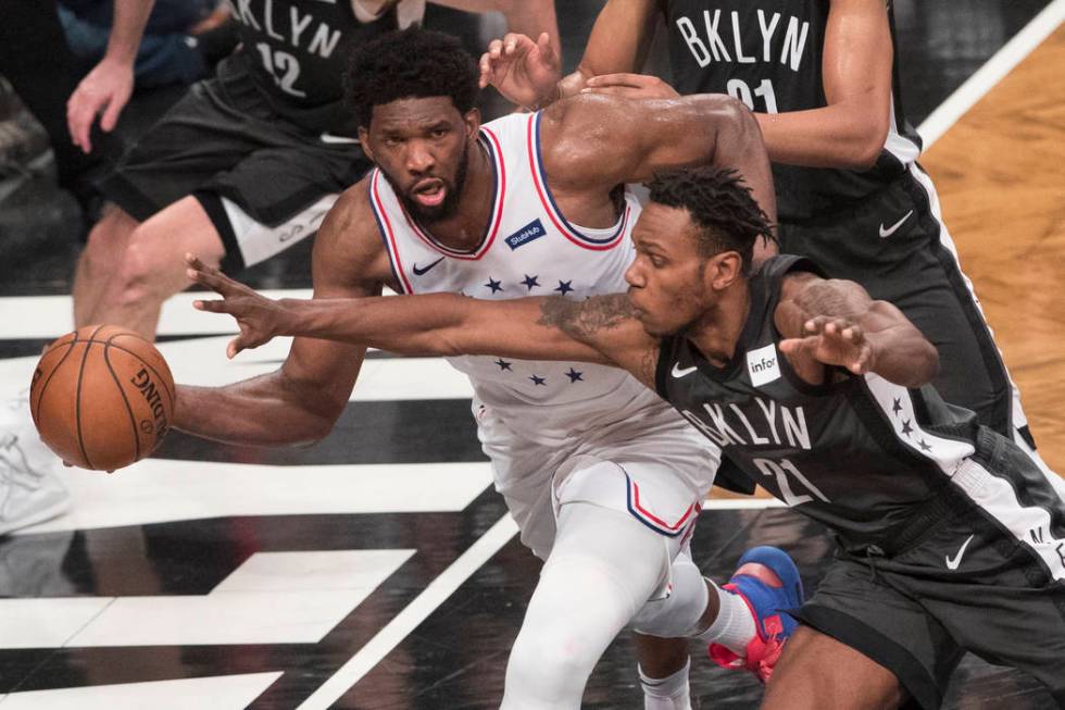 Philadelphia 76ers center Joel Embiid passes the ball around Brooklyn Nets guard Treveon Graham ...