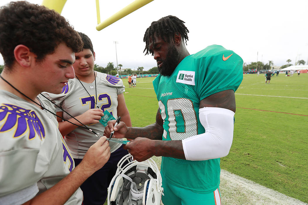 Miami Dolphins free safety Reshad Jones, right, signs autographs after the teams NFL football t ...