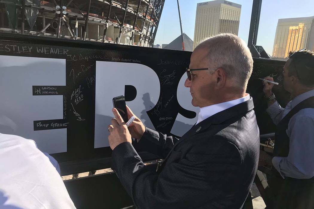 Raiders President Mark Badain takes a picture of his signature after he signed a beam that will ...