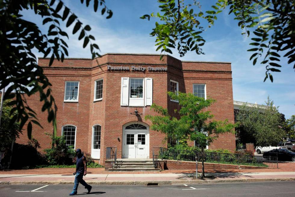 In this Monday, Aug. 5, 2019 photo a passer-by walks near an entrance to the Taunton Daily Gaze ...