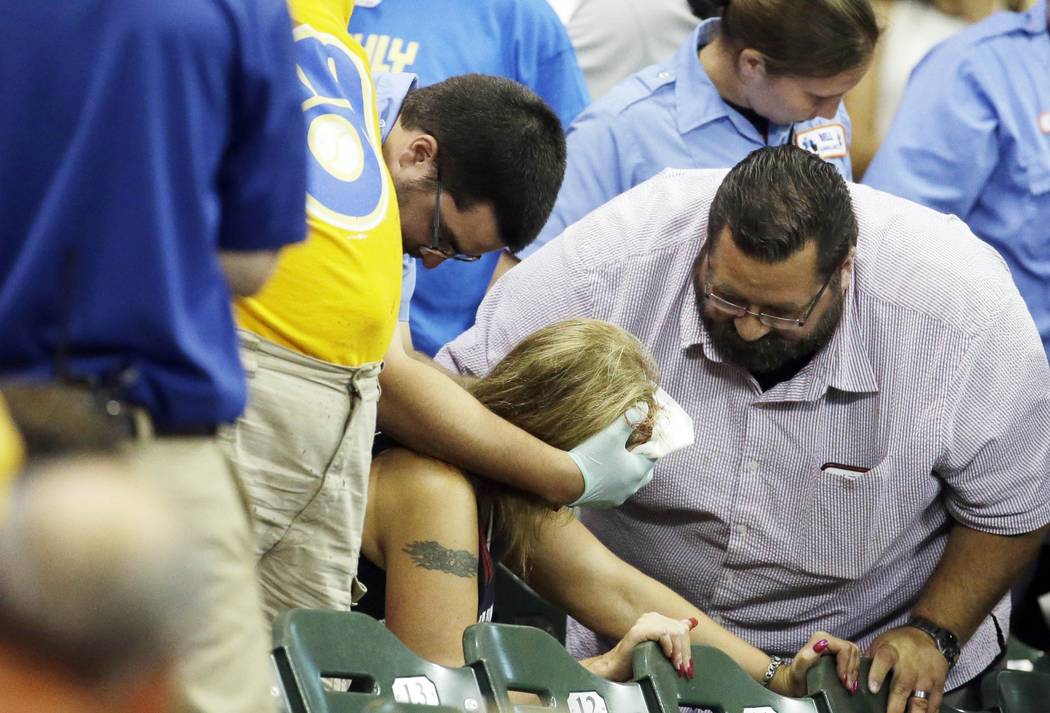A fan is helped after being hit by a foul ball during the ninth inning of a baseball game betwe ...