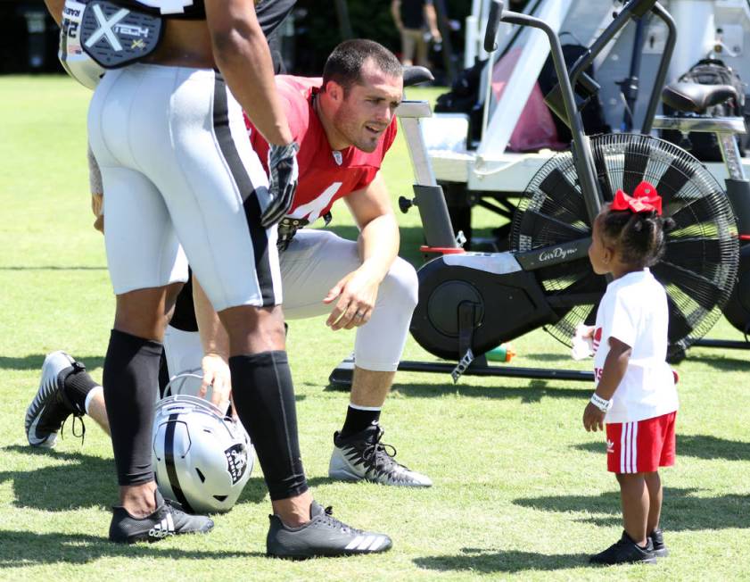 Oakland Raiders quarterback Derek Carr (4) talks to safety Johnathan Abram's two-year-old daug ...