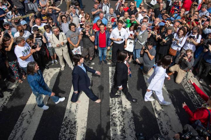 Thousands of fans gather to walk across the Abbey Road zebra crossing, on the 50th anniversary ...