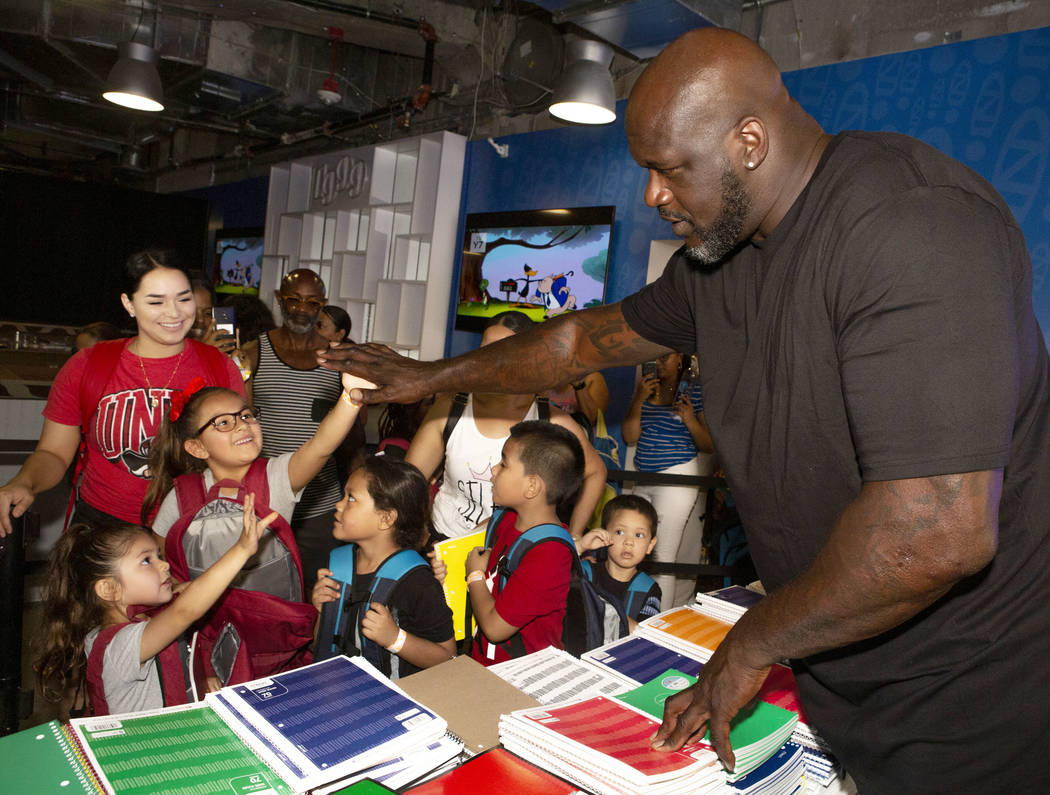Isabella Hidalgo, 7, center, gives a high-five to former NBA star Shaquille O'Neal, with her si ...
