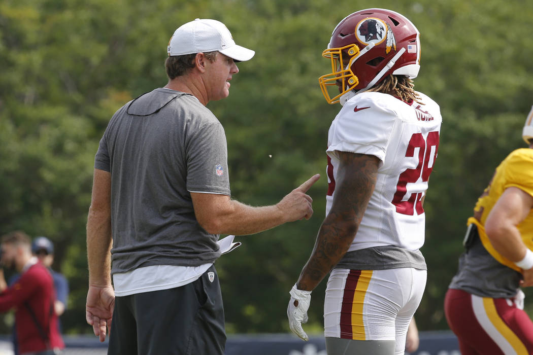 Washington Redskins head coach Jay Gruden, left, talks with running back Derrius Guice (29) dur ...