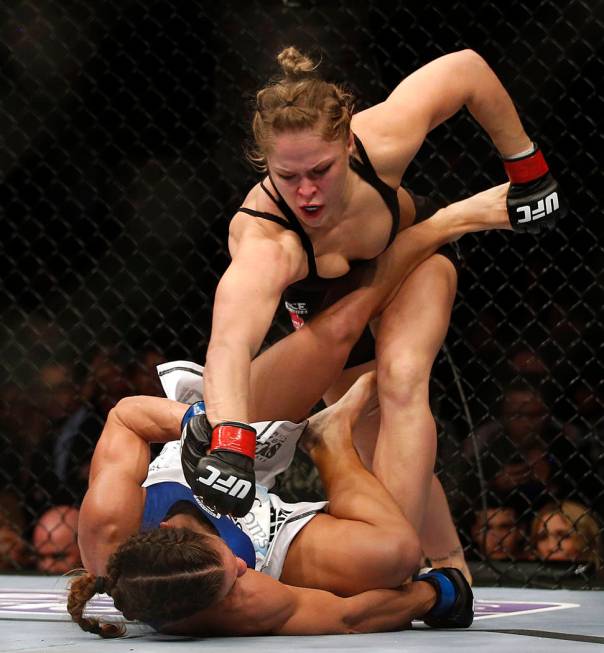 Ronda Rousey, top, punches Liz Carmouche during their UFC 157 women's bantamweight championship ...