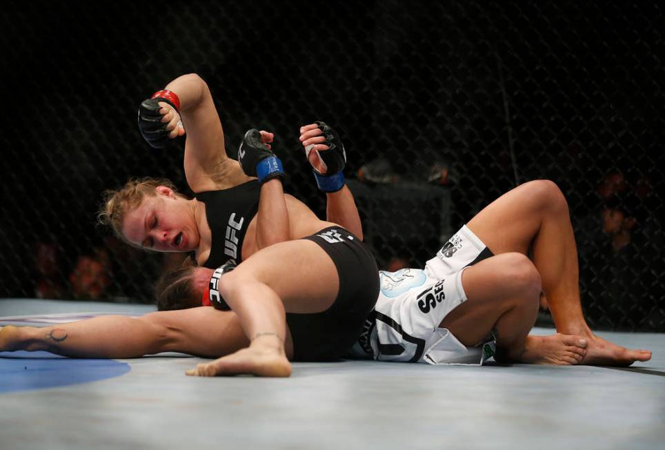 Ronda Rousey, top, punches Liz Carmouche during their UFC 157 women's bantamweight championship ...