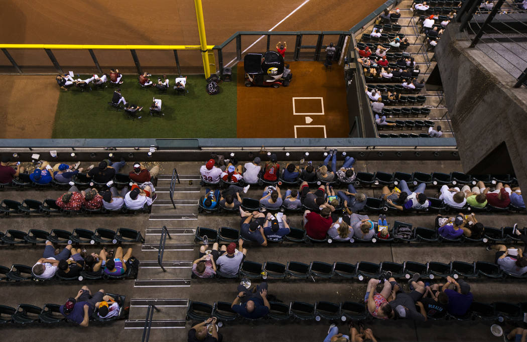 Fans watch the action as members of the Arizona Diamondbacks sit in the bullpen during a baseba ...