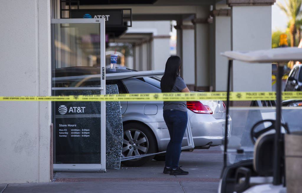 Las Vegas police investigate the scene where a driver in a car crashed into an AT&T store i ...