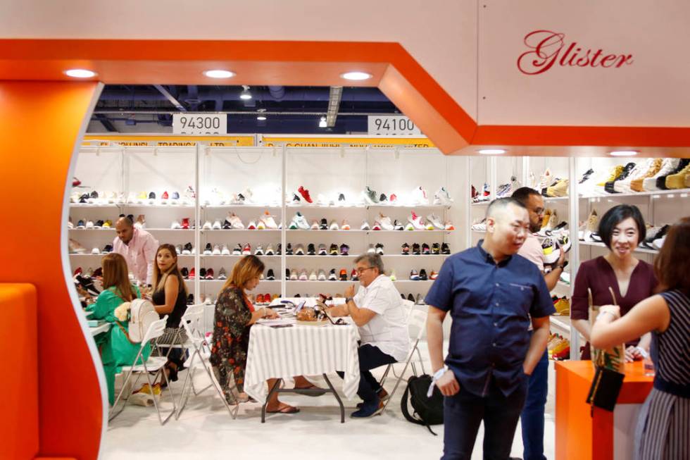 Consumers speak with exhibitor Elite Footwear during the first day of the MAGIC trade show at t ...