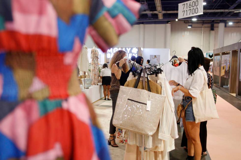 Attendees look at Molly Bracken collections on the show floor during the first day of the MAGIC ...