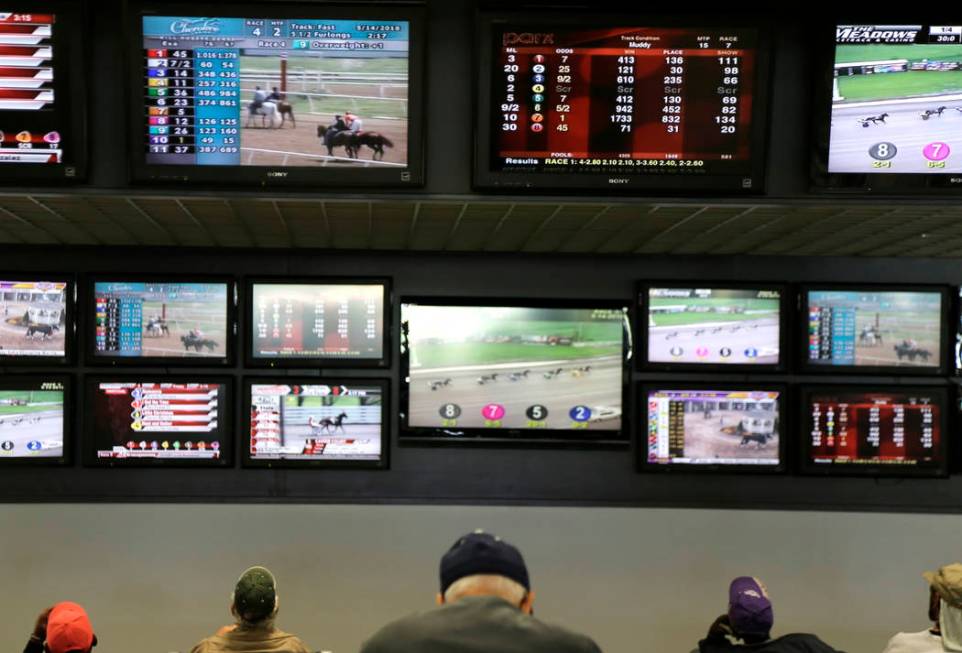 FILE - In this May 14, 2018, file photo, men watch horse racing on an array of screens at Monmo ...