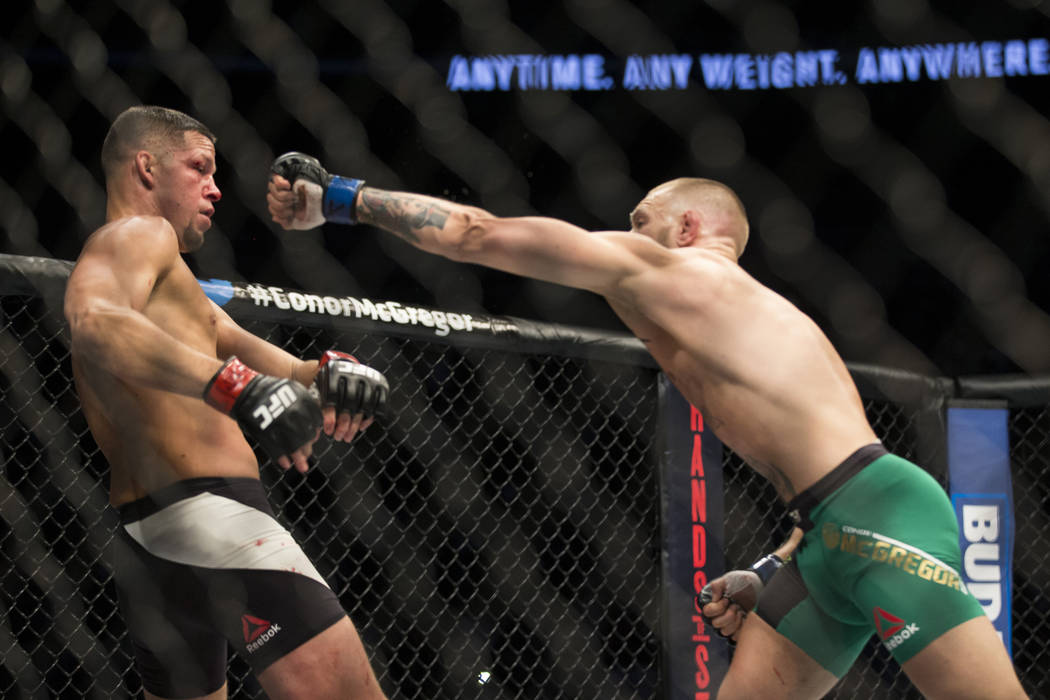 Nate Diaz, left, moves away from a punch against Conor McGregor in the welterweight bout during ...